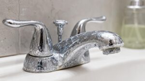 White mineral deposits caused by hard water on a bathroom faucet